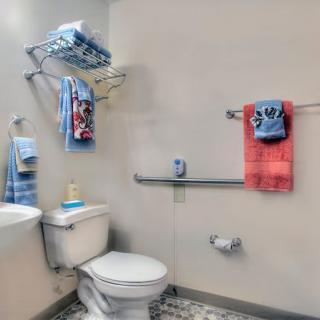 A tidy bathroom featuring a toilet, sink, and colorful towels on racks.