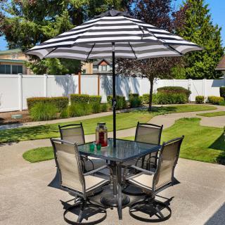 A patio set with a striped umbrella and four chairs on a sunny day.