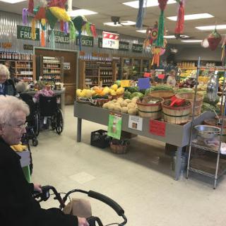 Elderly individuals shopping for fresh produce in a grocery store.