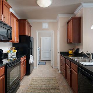 A modern kitchen with wooden cabinets and black countertops.