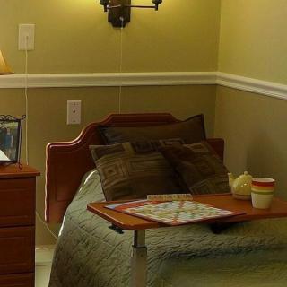 A cozy hospital room with a bed, tray table, and soft lighting.