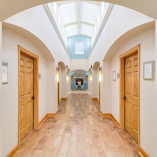 A brightly lit hallway with wooden doors and an arched ceiling.