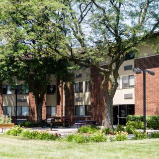 A brick building surrounded by trees and a well-maintained lawn.