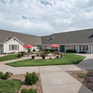 A building with a landscaped courtyard featuring red umbrellas and well-maintained lawns.