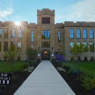 A historic building with a sunlit facade and landscaped pathway.