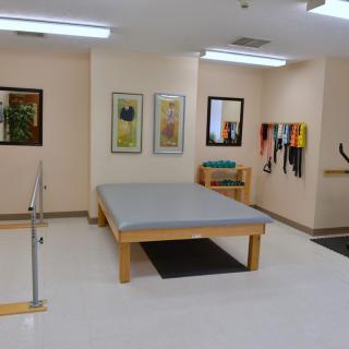 A physical therapy room equipped with exercise equipment and a large therapy table.
