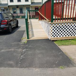 A wheelchair accessible ramp connecting the sidewalk to the building, situated next to a parked car.