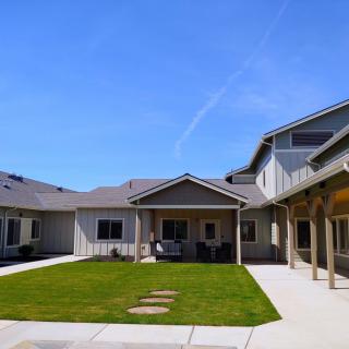 A view of a residential courtyard with a well-maintained lawn under a clear blue sky.