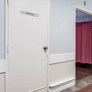A restroom door next to a curtained area in a well-lit interior space.