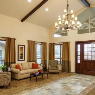 A spacious living room with a vaulted ceiling, featuring a chandelier, comfortable seating, and tasteful decor.