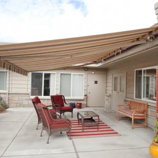 An outdoor patio with comfortable seating and a shade sail providing cover.