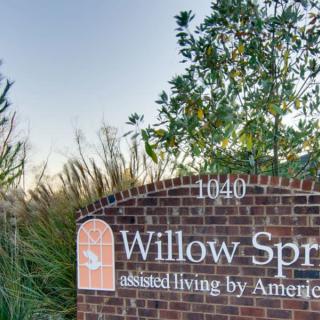 Sign for Willow Springs assisted living facility surrounded by trees and grass.
