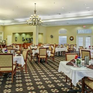 A spacious dining room with elegantly set tables and a chandelier hanging from the ceiling.