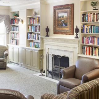 A cozy living room with built-in bookshelves, a fireplace, and comfortable armchairs.