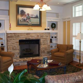 A cozy living room with a stone fireplace, armchairs, and decorative accents.