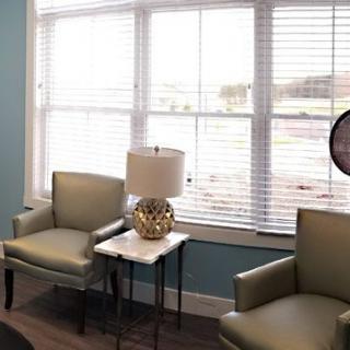 A cozy living room nook with two armchairs, a side table, and a lamp by a window.