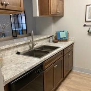 A modern kitchen with wooden cabinets and a marble countertop.