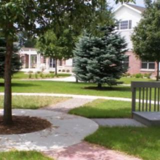 A well-maintained garden with a winding pathway, surrounded by trees and a bench.