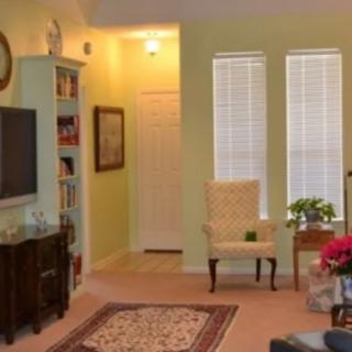 A cozy living room with a TV, bookshelf, and comfortable seating.