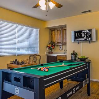 A cozy game room featuring a pool table and chess set, with a television mounted on the wall.