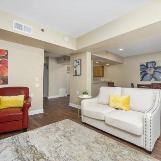 A cozy living room with a white sofa, a red armchair, and colorful artwork on the walls.