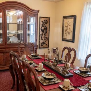 A dining room with a fully set table and a china cabinet in the background.