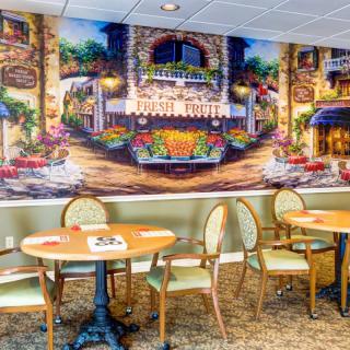 A cozy cafe interior with vibrant mural artwork and neatly arranged seating.