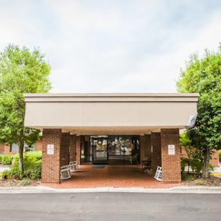 A building entrance with a covered entryway surrounded by trees.
