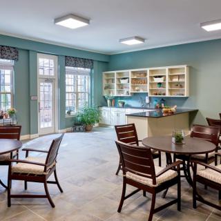 A modern kitchen and dining area with wooden tables and chairs, featuring a bright and inviting atmosphere.