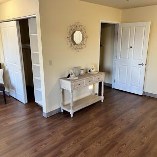 A cozy home interior featuring a hardwood floor, a console table with decor items, and a mirror on the wall.