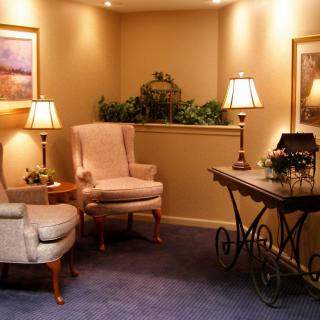 A cozy living room with two armchairs, a decorative table, and warm lighting.