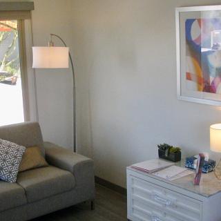 A cozy living room with a sofa, floor lamp, and abstract artwork on the wall.
