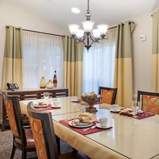 A cozy dining room with a stylish chandelier and neatly arranged table settings.