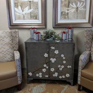 A cozy seating area featuring elegant chairs, a decorative cabinet adorned with floral designs, and framed artwork.