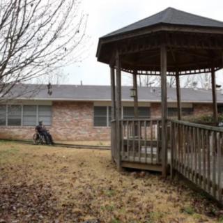 A backyard scene featuring a wooden gazebo next to a brick house.