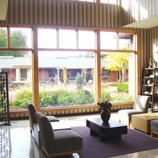 A serene and modern lounge area with large windows offering a view of lush greenery.