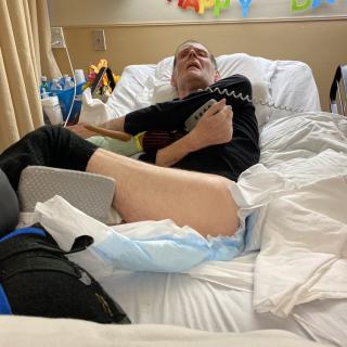A patient lying on a hospital bed with medical equipment nearby.
