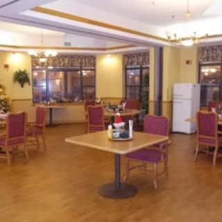 An empty dining area with neatly arranged tables and chairs, featuring warm lighting and festive decorations.