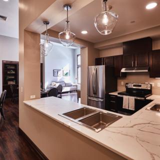 A modern kitchen with dark wood cabinets, stainless steel appliances, and stylish pendant lighting.