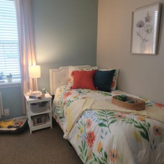A cozy bedroom featuring colorful bedding and a softly lit lamp on a nightstand.