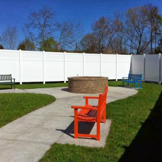 A cozy outdoor seating area featuring vibrant chairs, a fire pit, and a winding pathway.