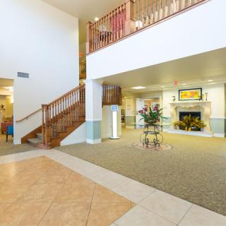A spacious lobby area featuring a staircase with wooden railings, a fireplace, and various pieces of furniture.