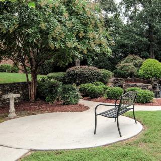 A tranquil garden scene with a bench and well-maintained shrubbery.