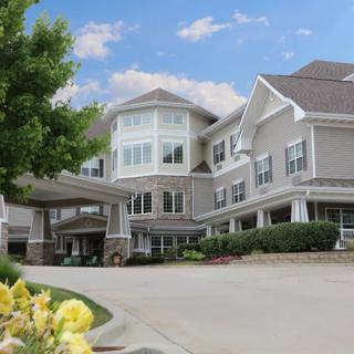 A large residential building with a neatly landscaped entrance and driveway.