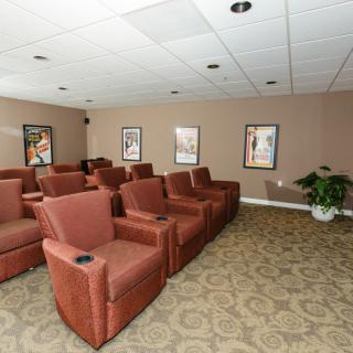 A cozy home theater room featuring comfortable recliner seating and walls adorned with posters.