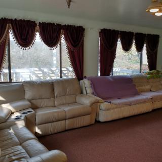A cozy living room with a beige sectional sofa and large windows adorned with dark red curtains.