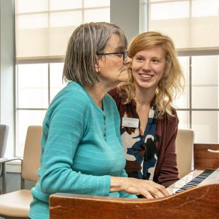 Two women enjoying playing the piano together indoors.