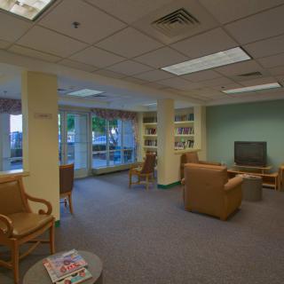 A cozy waiting room with comfortable chairs, a television, bookshelves, and a collection of magazines.