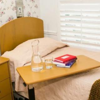 A cozy bedroom with a small bed, side table, and study materials.