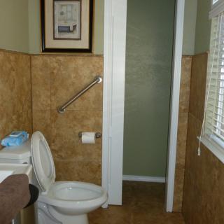 A bathroom with a toilet, tiled walls, and a grab bar near the window.